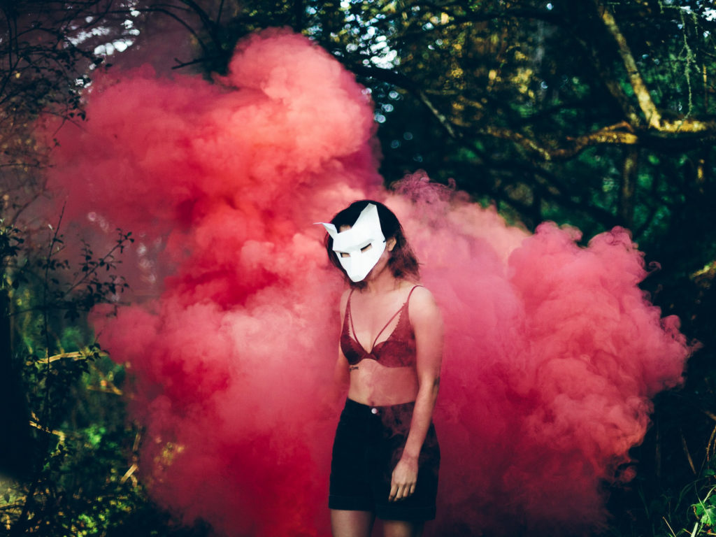 règles- femme portant un masque devant une fumée rouge