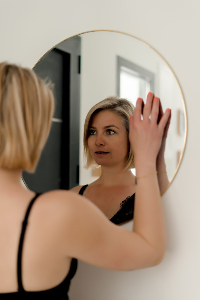 Femme blonde se regardant dans un miroir lors d'une séance boudoir - guérir les blessures émotionnelles