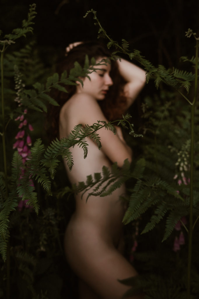 Une femme nue posant dans les fougères lors d'une séance boudoir naturel