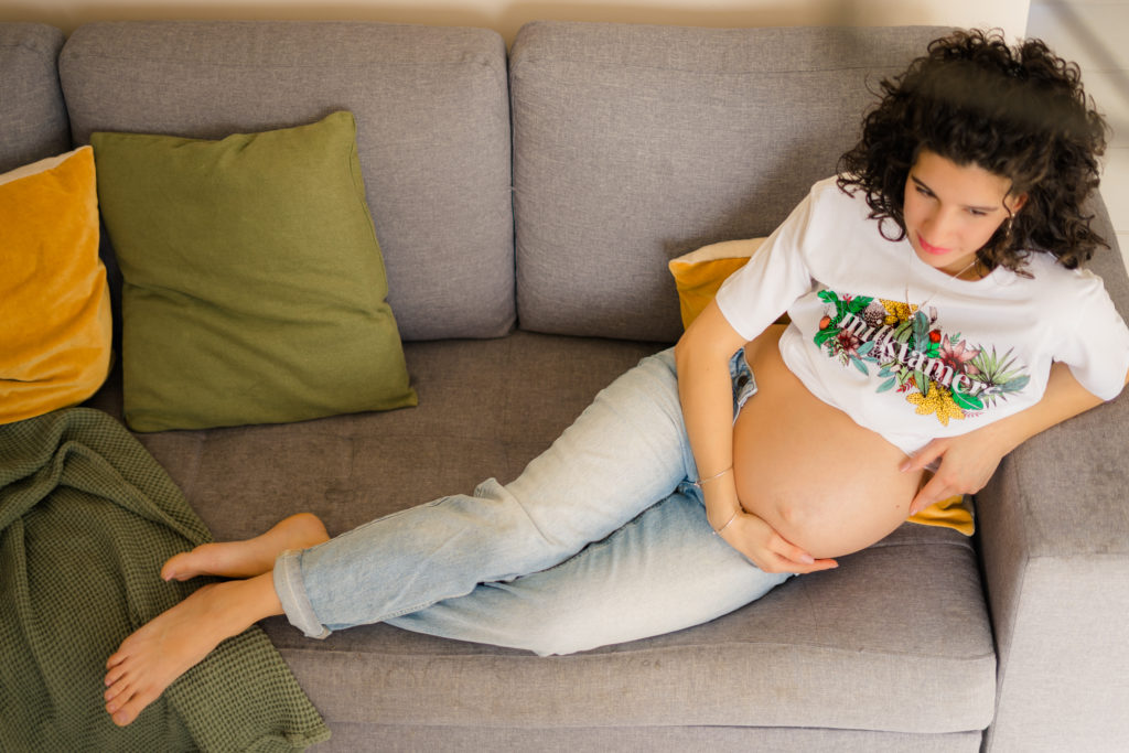 Femme enceinte allongée sur un canapé pendant sa séance photo maternité à Niort
