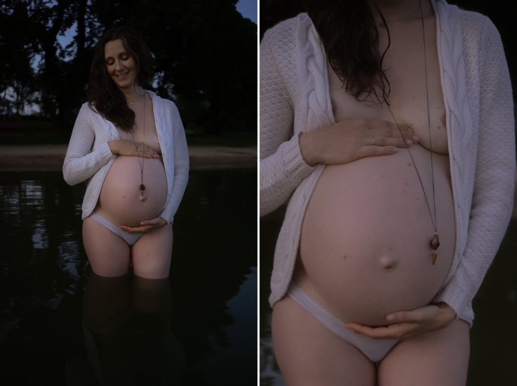 Femme enceinte portant un gilet ouvert sur son ventre lors d'une séance photos de maternité dans un lac
