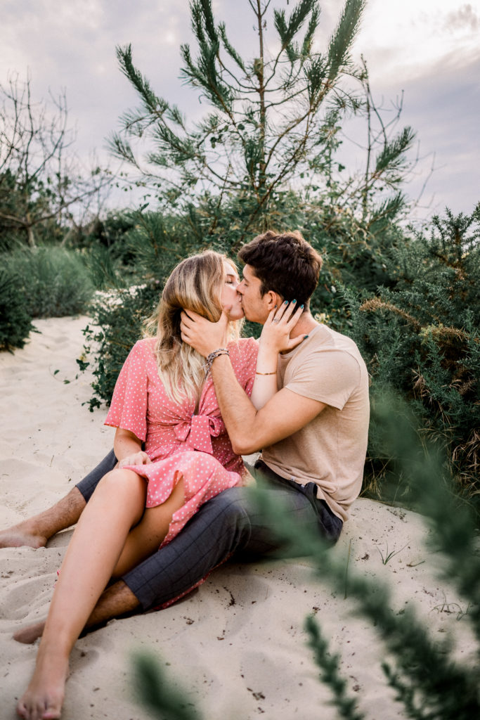 les saisons du couple : le printemps - un homme et une femme assis dans le sable s'embrassent
