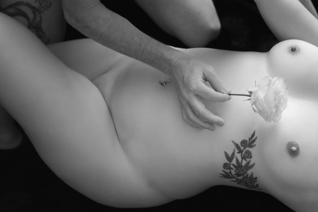 Photo d'un homme caressant délicatement le corps nu d'une femme avec une rose pour briser la routine de couple